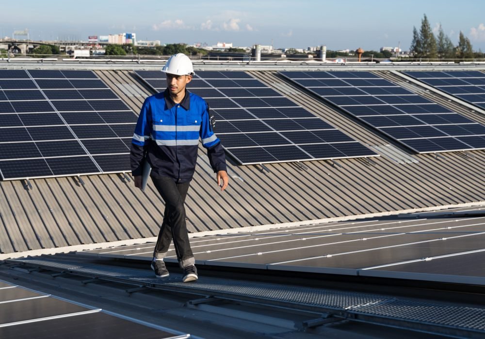 Portrait of Asian engineer on background field of photovoltaic solar panels solar cells on roof top factory.