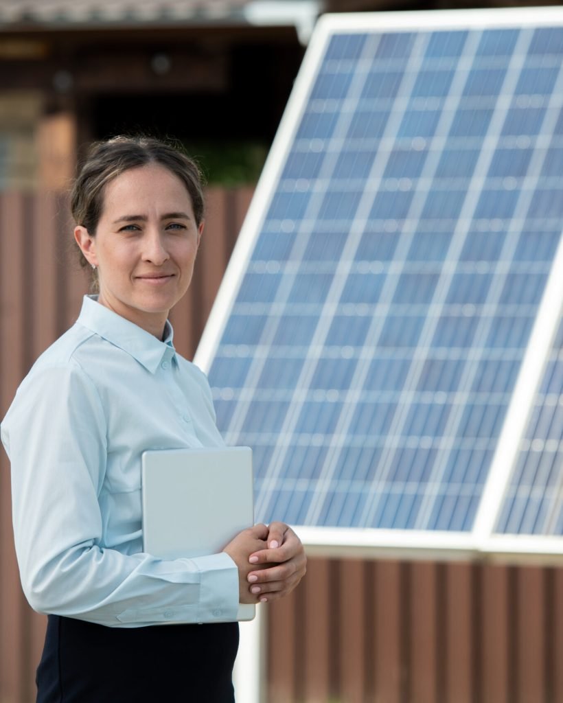 Portrait of smiling manager of solar panel installation company with tablet computer standing outdoors